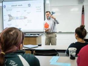 Dr. Knight demonstrating rocket physics in front of class